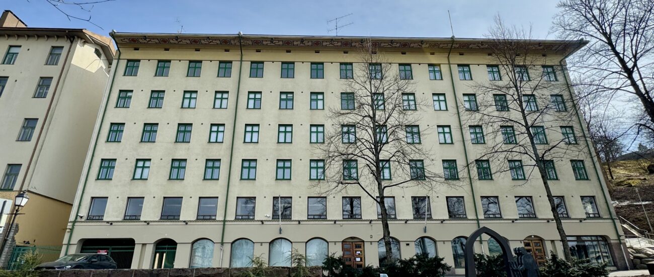 Olavintien kiinteistö kuvattuna etualalta. Rakennus on vaaleankeltainen sekä ikkunoissa on vihreät puitteet.