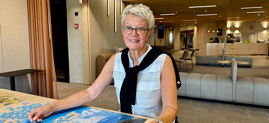 Henkilö ratkoo palapeliä ja hymyilee kameraan.