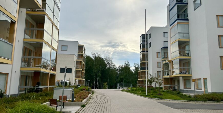 Fastigheten Nuttukujas innergård. I mitten av gården går det en väg som är omringas av grönska. I bakrunden finns det träd.