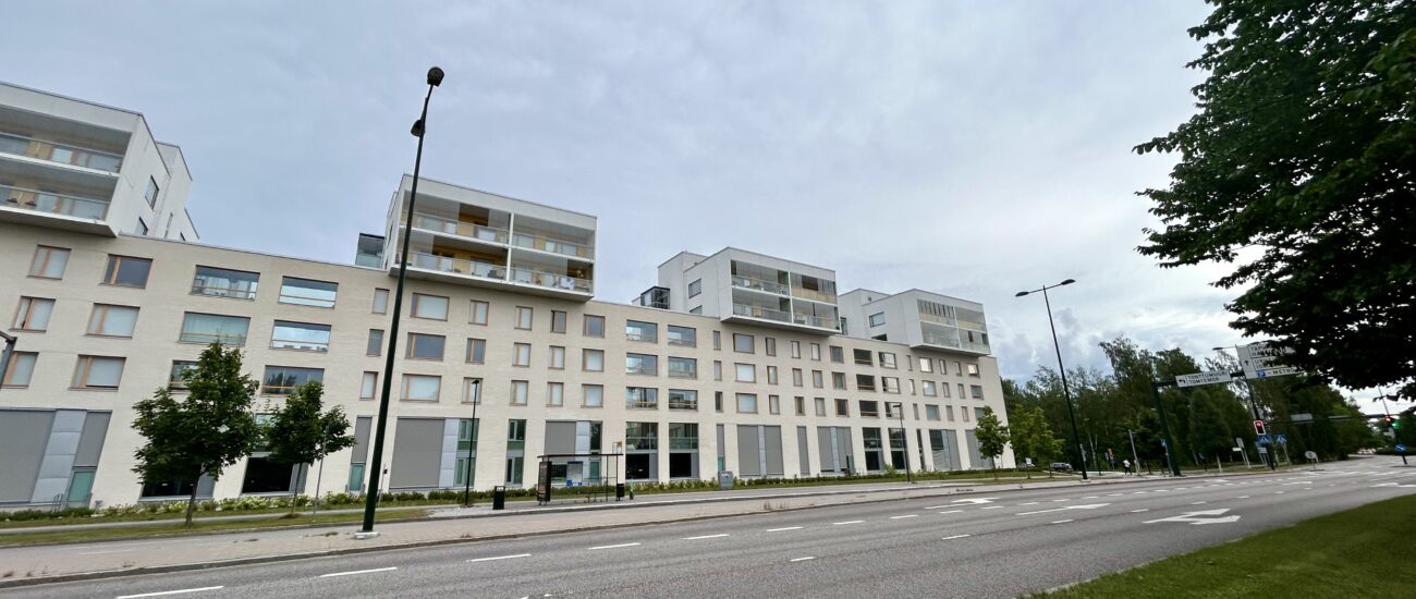 Veritas fastighet på Koltgränden fotograferad från avstånd. På framsidan av byggnaden finns det en rad av träd och en bilväg.