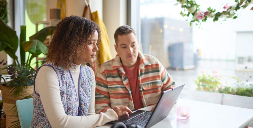 Man and women are looking a laptop in a cafe.