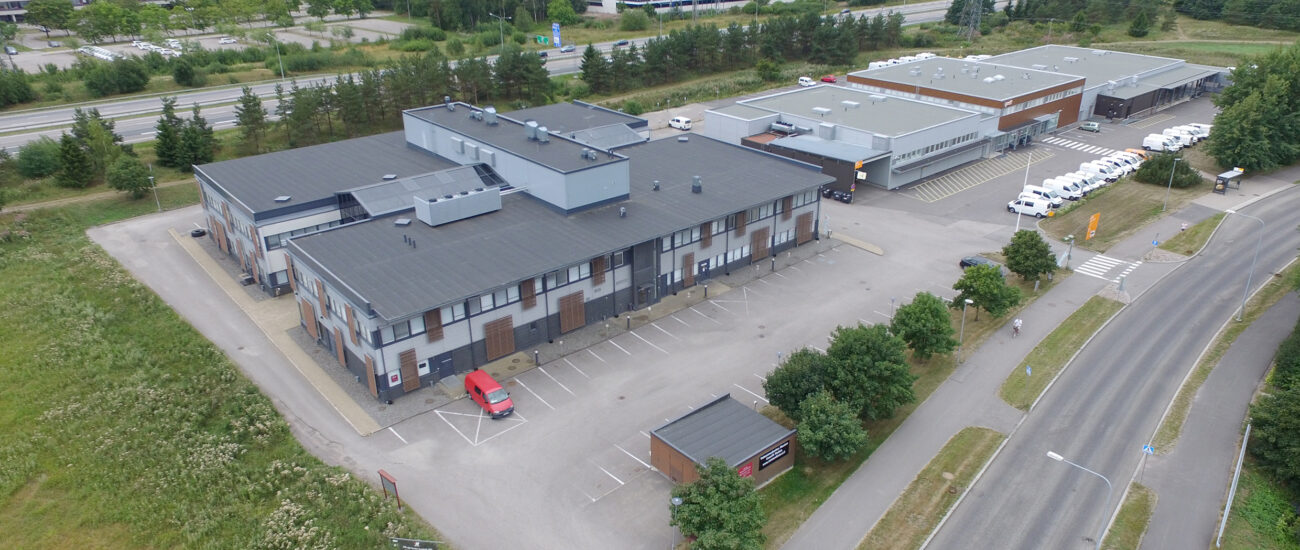 Nuijalantien kiinteistö ilmasta kuvattuna. Taustalla näkyy Turunväylä ja rakennuksia. Muuten ympäristö on vehreä. Pihalla on parkissa muutamia autoja.